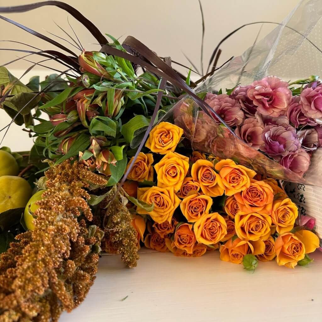 Fall flower arrangement with rich tones of burgundy, orange, rust, and golden yellow, styled for a warm seasonal centerpiece.