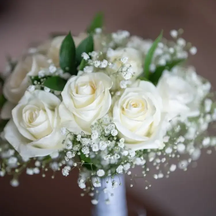 Monochromatic floral arrangement with white roses and baby's breath, accented with greenery