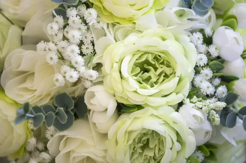 Close-up of a green and white St. Patrick's Day bouquet featuring green ranunculus, white roses, baby's breath, and eucalyptus